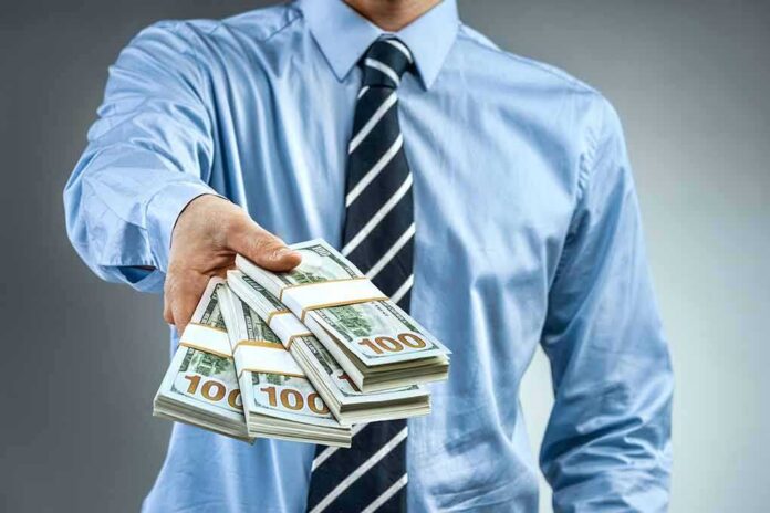 Person in business attire offering bundles of US dollar bills