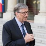 older man in suit speaking outside a building