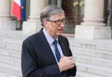 older man in suit speaking outside a building