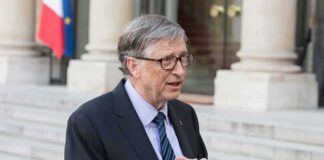 older man in suit speaking outside a building