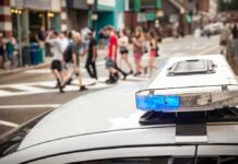 Police car lightbar with blue light near a busy crosswalk
