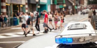 Police car lightbar with blue light near a busy crosswalk