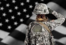 Soldier in camouflage saluting before a U.S. flag