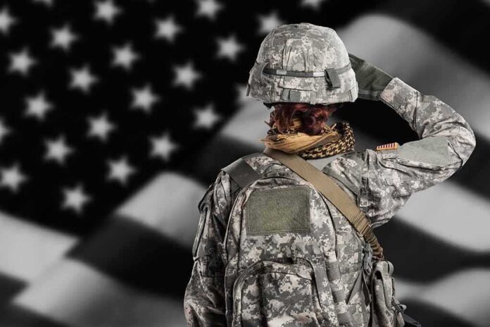 Soldier in camouflage saluting before a U.S. flag