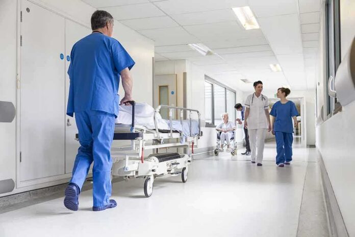 shutterstock_156022646 Hospital staff in scrubs walking in a bright corridor