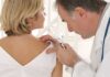 Doctor examining a patients skin with a magnifying glass