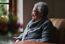 Elderly woman sitting by a window in a cozy sweater