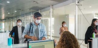 masked travelers line up at an airport check-in counter