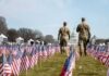 Two soldiers walk among American flags toward the U.S. Capitol