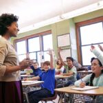 Florida Schools Take On Communism Teacher engaging with students raising hands in a classroom