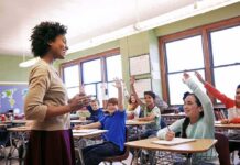 Teacher engaging with students raising hands in a classroom
