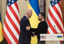 Two men shake hands at a podium with U.S. and Ukrainian flags