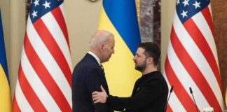Two men shake hands at a podium with U.S. and Ukrainian flags