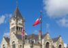 Historic stone courthouse with clock tower and flags