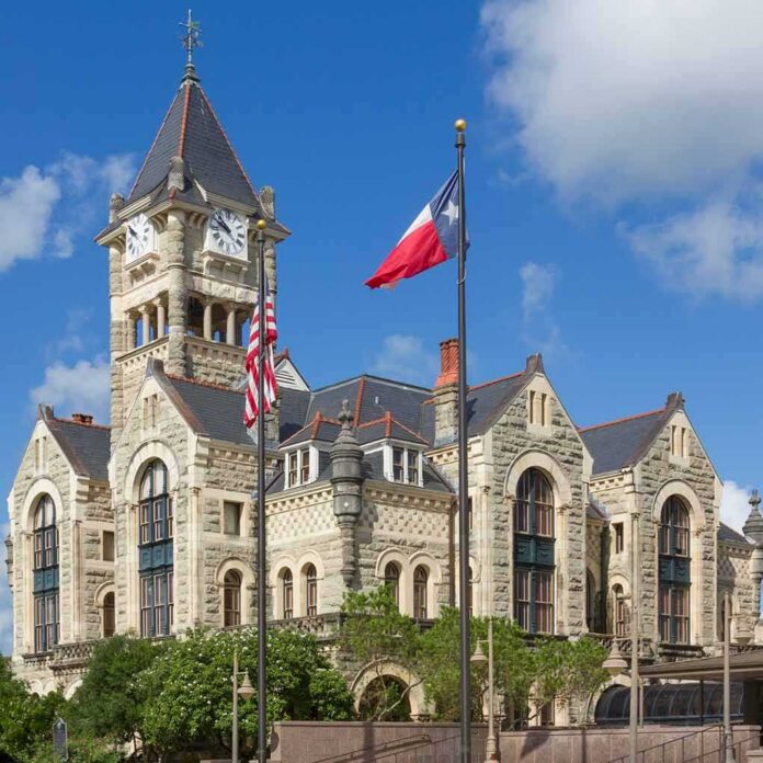 Historic stone courthouse with clock tower and flags