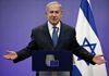 man in suit speaking at a podium with Israeli flag