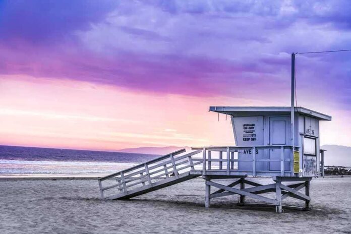 shutterstock_1089187769 Lifeguard tower on a sandy beach at sunset with colorful sky