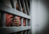 Hand gripping jail bars