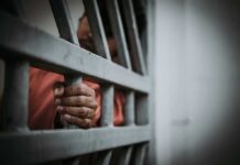 Top Cop Dragged Into Rape Scandal Hand gripping jail bars