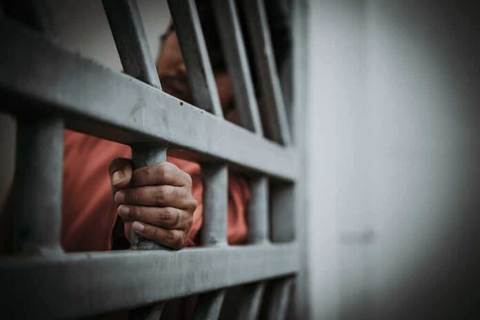 shutterstock_1110430886 Hand gripping jail bars