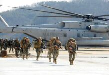 Marines Dangle $15K – But For What? Soldiers disembark and walk past a large military helicopter