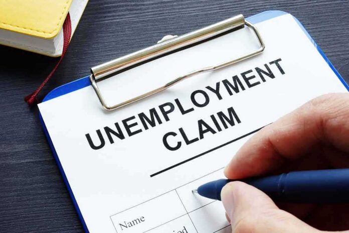 shutterstock_1144538276 Unemployment claim form on clipboard with hand holding pen