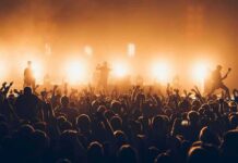 Ed Sheeran Apologizes – Backlash Erupts Rock band performing on stage with bright backlights and cheering crowd