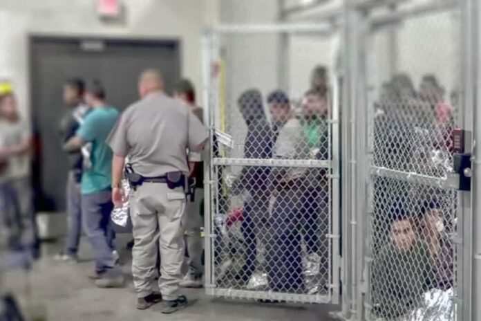 shutterstock_1229072188 People standing inside chain-link holding area with an officer nearby