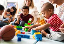 Karyn Polito with toddlers building blocks on a play mat