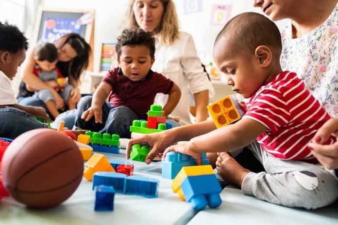 Karyn Polito with toddlers building blocks on a play mat