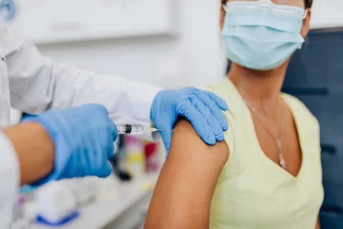 Healthcare worker gives vaccine injection to masked patient