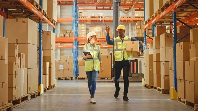shutterstock_1848611116 Warehouse workers walking among shelves with boxes