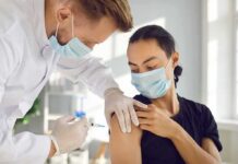 Medicare Promise, Math Panic Healthcare worker giving a masked patient a vaccine in the upper arm
