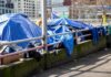 Tents covered with blue tarps along a city sidewalk