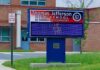 Electronic school marquee in front of a brick high school