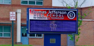 Electronic school marquee in front of a brick high school