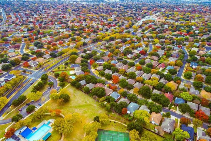 shutterstock_2010099641 Aerial view of suburban neighborhood with tree-lined streets in autumn