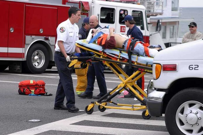 Gary Patterson on a stretcher being moved by paramedics near fire trucks and an ambulance