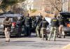 Prosecutors Cry Murder, Internet Hails Hero Police and sheriff officers gather around vehicles on a suburban street