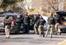 Prosecutors Cry Murder, Internet Hails Hero Police and sheriff officers gather around vehicles on a suburban street