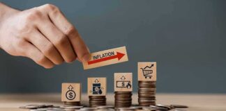 Hand placing inflation label over stacked coins with economy icons