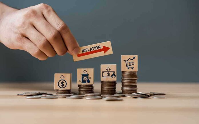 Hand placing inflation label over stacked coins with economy icons