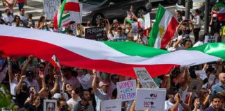 Protest crowd with flags and signs; Seyed Ebrahim Raisi, La Parka, Brian Robiskie, Philly Brown, Miguel Francisco Barragán Andrade present