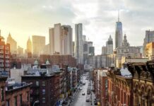 Priced-Out New Yorkers Flood Philly City street leading to a skyline of modern and historic skyscrapers at sunset
