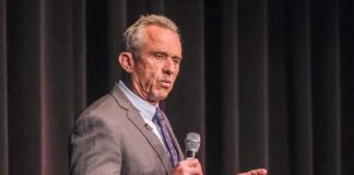 man in a suit speaking into a microphone on stage