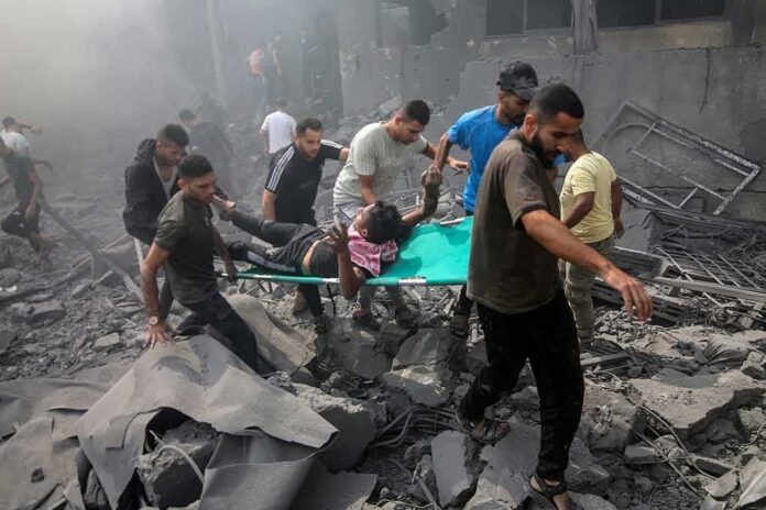 shutterstock_2374212961 Rescuers carry an injured person on a stretcher through rubble