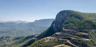 Winding mountain road with sharp switchbacks on a green hillside