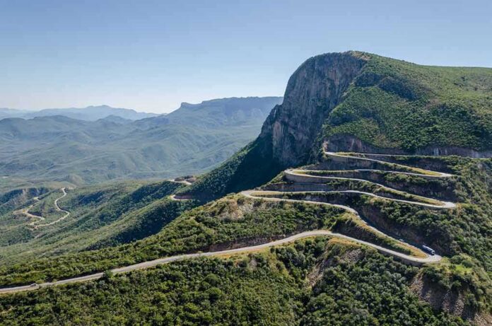 shutterstock_518565091 Winding mountain road with sharp switchbacks on a green hillside