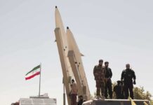 Trump Weighs ‘Annihilate’ Option Soldiers stand beside large missiles at an outdoor display