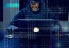 Person in hoodie using a laptop with binary code overlay